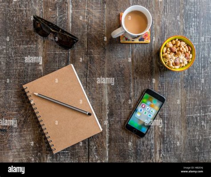Smartphone, notebook with pen, sunglasses, coffee and nuts, snacks on a wooden table VARIOUS